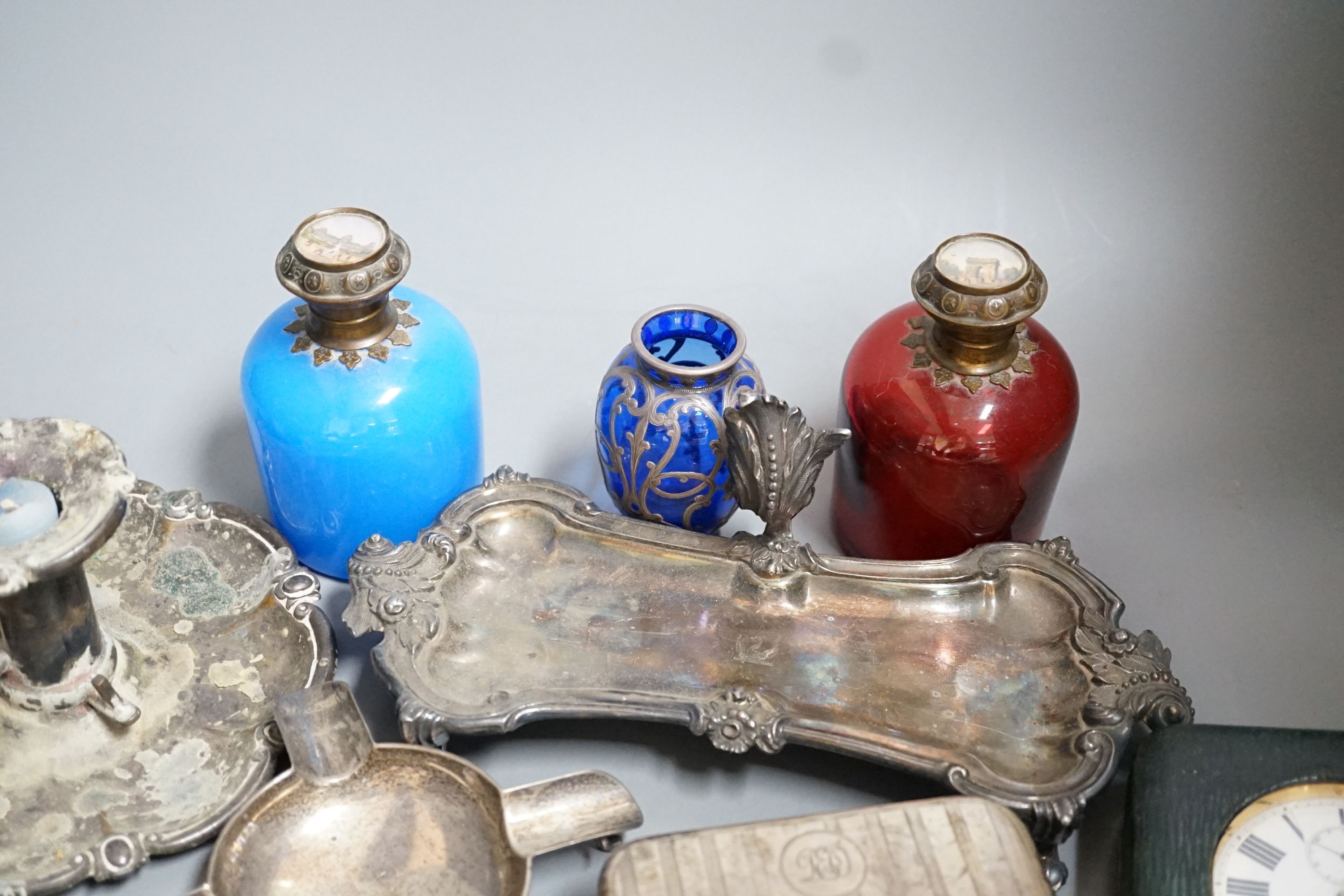 An Edwardian silver mounted travelling pocket watch case with 8-day pocket watch, one other travelling pocket watch in case, a silver mounted cigarette box, a silver ashtray, a plated snuffers stand and plated chambersti